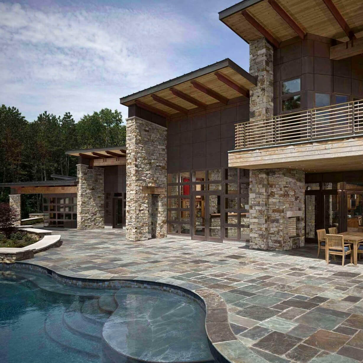 Modern stone house patio with curving pool