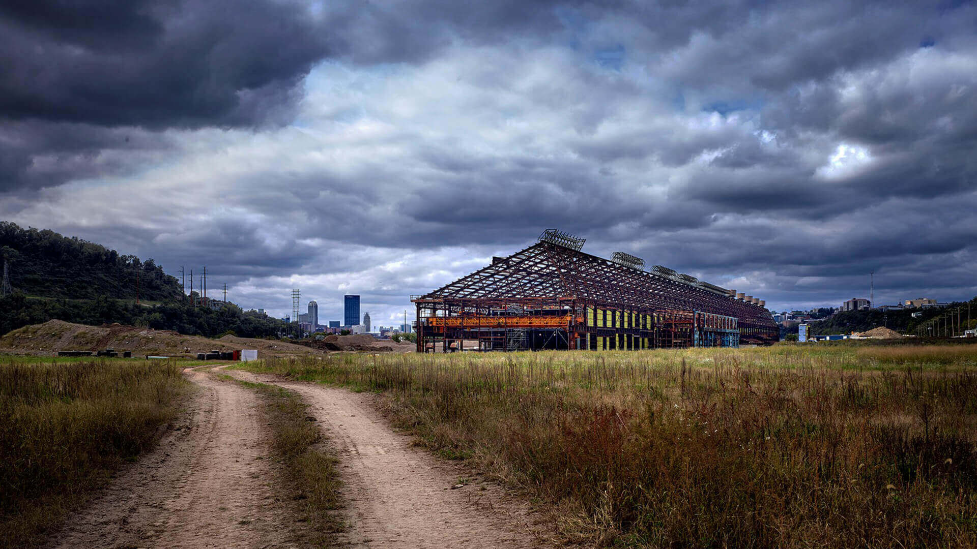 Dirt road to abandoned industrial skeleton under clouds