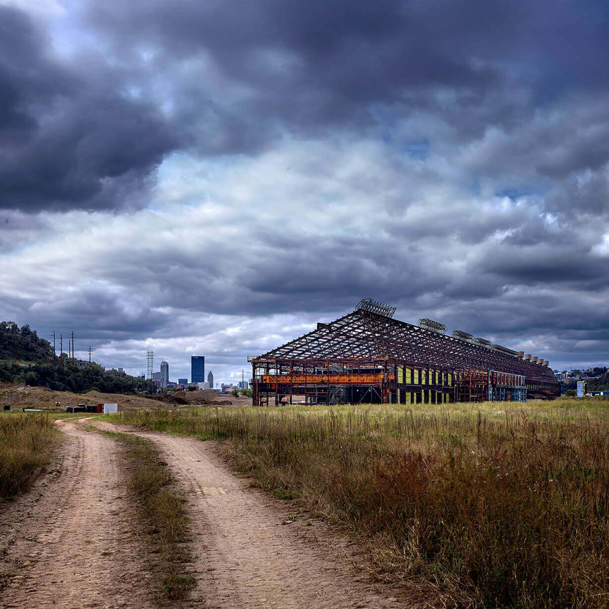 Dirt road to abandoned industrial warehouse under clouds