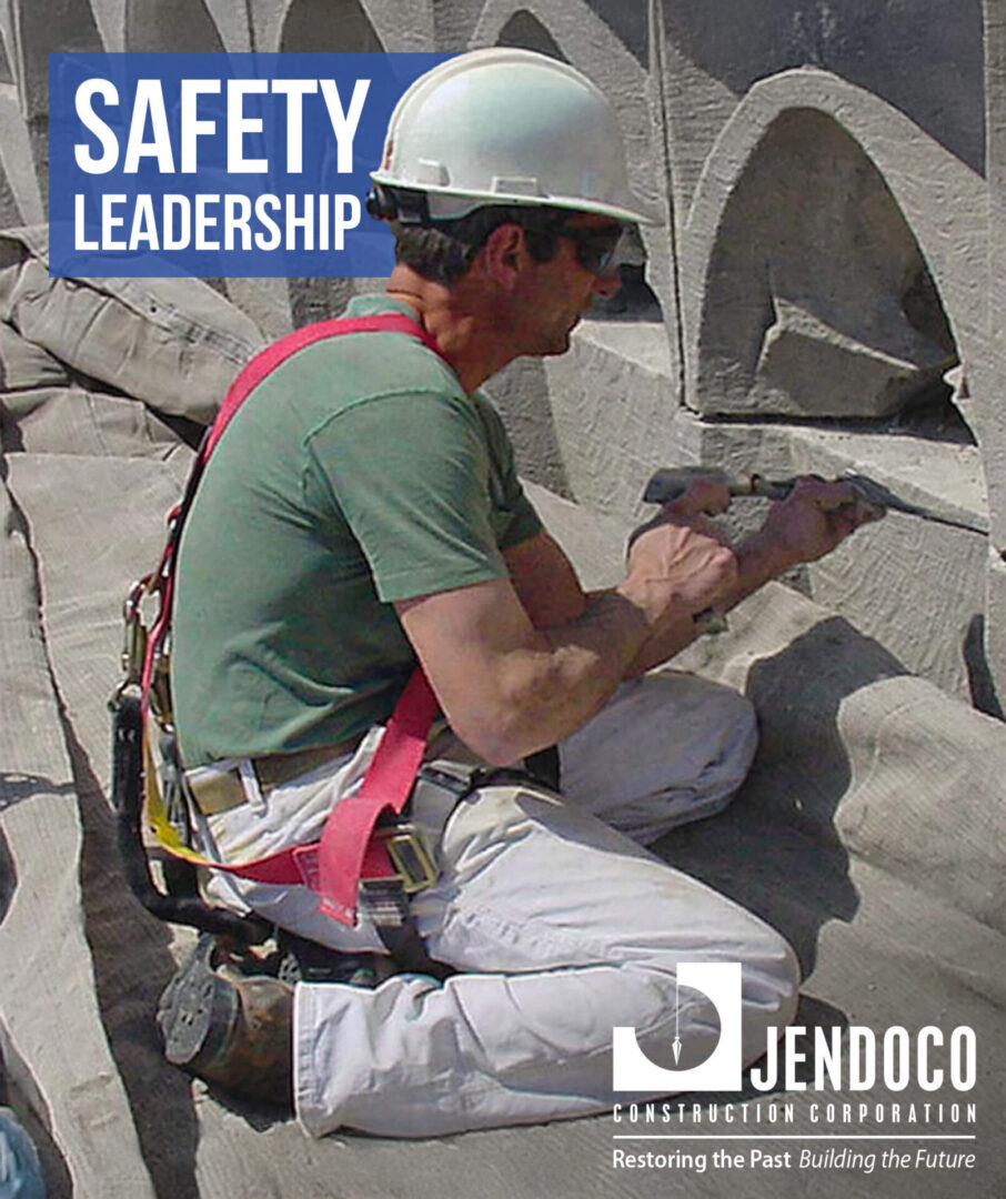 Construction worker with harness carving concrete facade