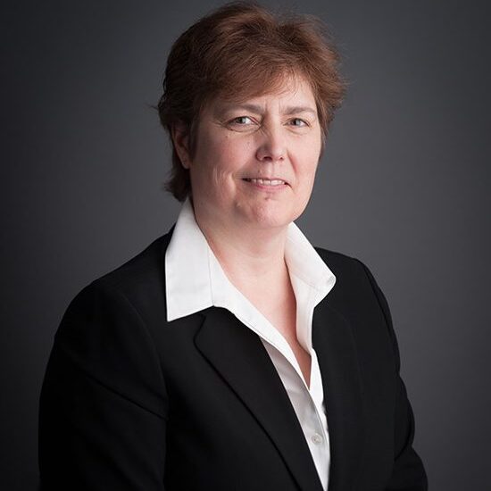 Person in formal attire against dark background.