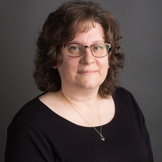 Woman with glasses and curly brown hair.