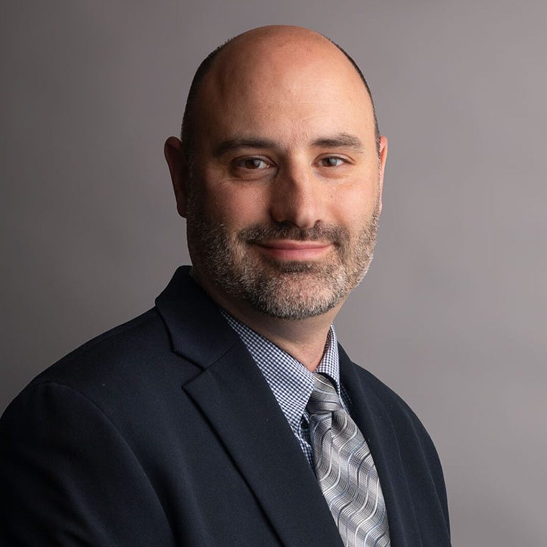 Professional headshot of smiling man in suit